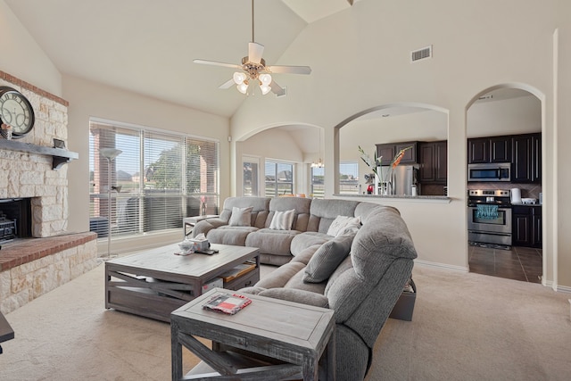 carpeted living room with ceiling fan, high vaulted ceiling, and a fireplace