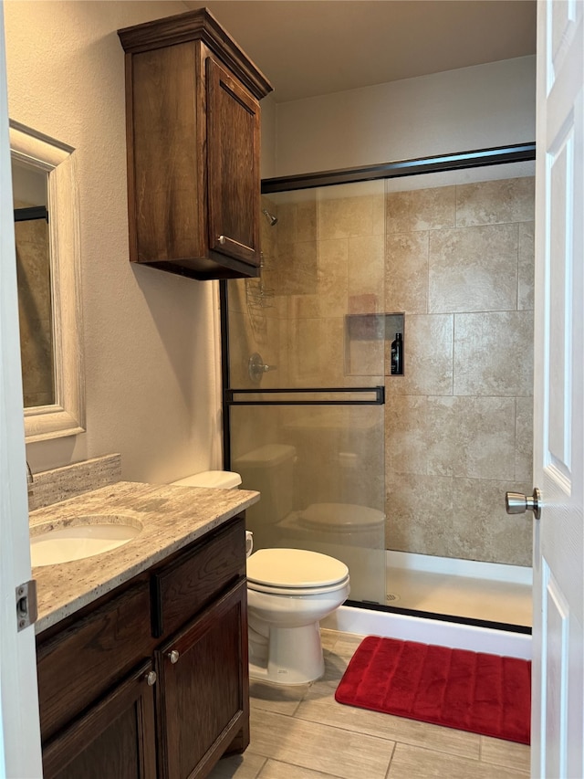 bathroom featuring toilet, an enclosed shower, and vanity