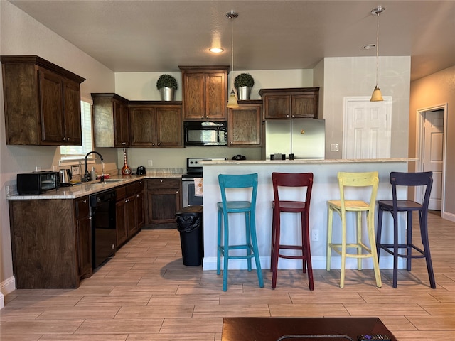 kitchen with black appliances, sink, a kitchen island, and hanging light fixtures