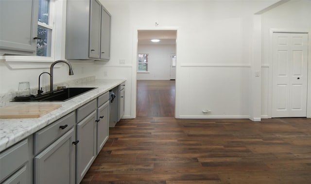 kitchen featuring gray cabinets, dark hardwood / wood-style flooring, light stone countertops, and sink