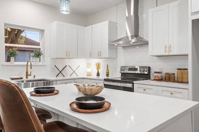 kitchen featuring tasteful backsplash, wall chimney exhaust hood, pendant lighting, electric range, and white cabinetry