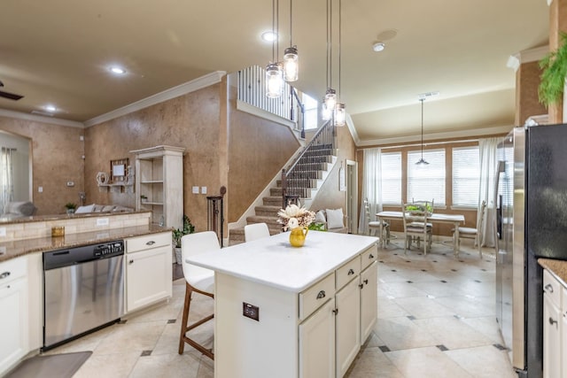 kitchen with a breakfast bar area, hanging light fixtures, stainless steel appliances, a center island, and white cabinets