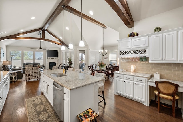 kitchen featuring a kitchen island with sink, sink, a kitchen bar, pendant lighting, and white cabinetry