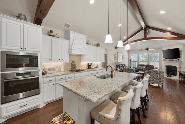 kitchen with sink, hanging light fixtures, white cabinetry, ceiling fan, and light stone counters