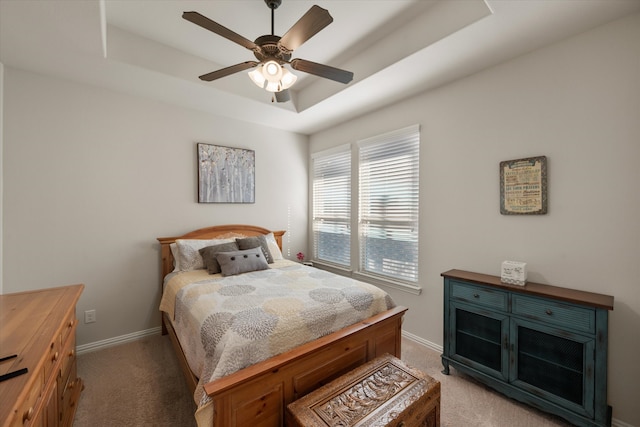 bedroom featuring ceiling fan, a tray ceiling, and light colored carpet