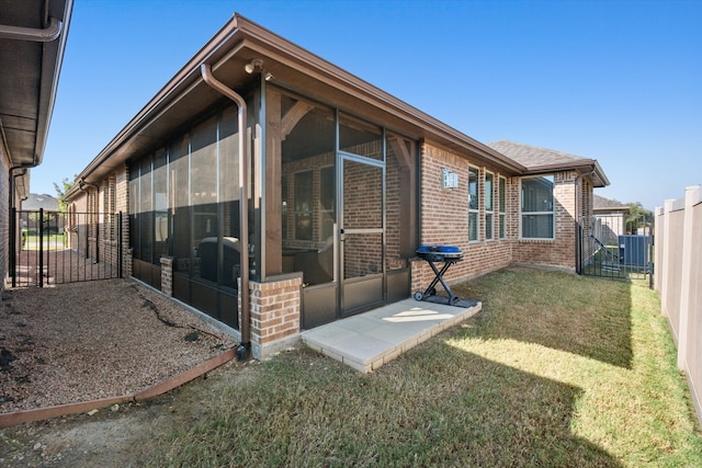 rear view of property with central air condition unit, a lawn, and a sunroom