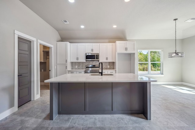 kitchen with stainless steel appliances, sink, vaulted ceiling, decorative light fixtures, and white cabinetry