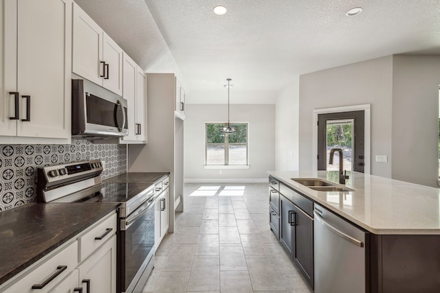 kitchen featuring a textured ceiling, white cabinetry, sink, pendant lighting, and stainless steel appliances