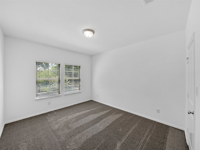 unfurnished room featuring dark carpet