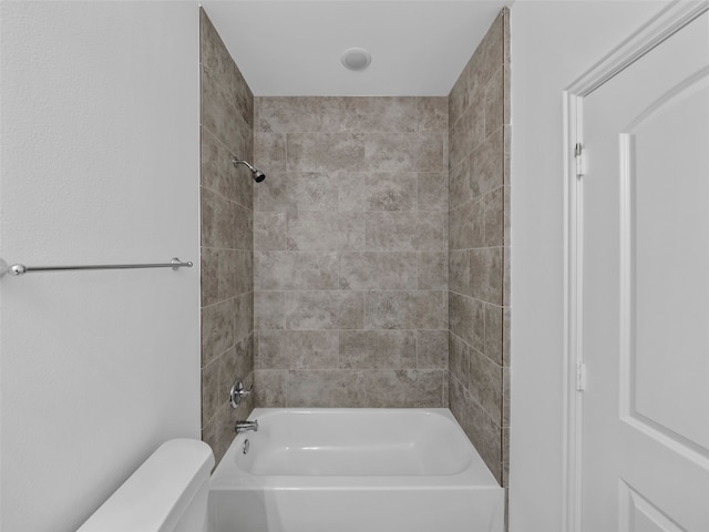 bathroom featuring tiled shower / bath combo and toilet