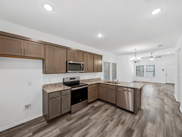 kitchen featuring kitchen peninsula, hanging light fixtures, wood-type flooring, sink, and stainless steel appliances