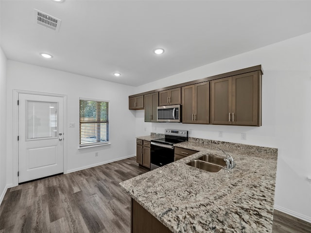 kitchen featuring sink, dark hardwood / wood-style flooring, stainless steel appliances, dark brown cabinetry, and light stone counters