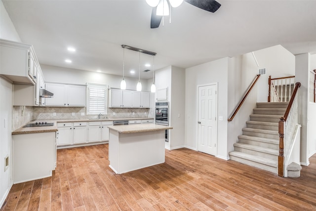 kitchen with oven, light hardwood / wood-style flooring, a center island, and pendant lighting