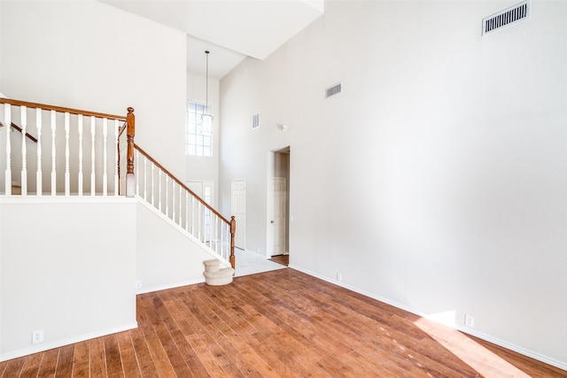 interior space featuring an inviting chandelier, hardwood / wood-style flooring, and a high ceiling