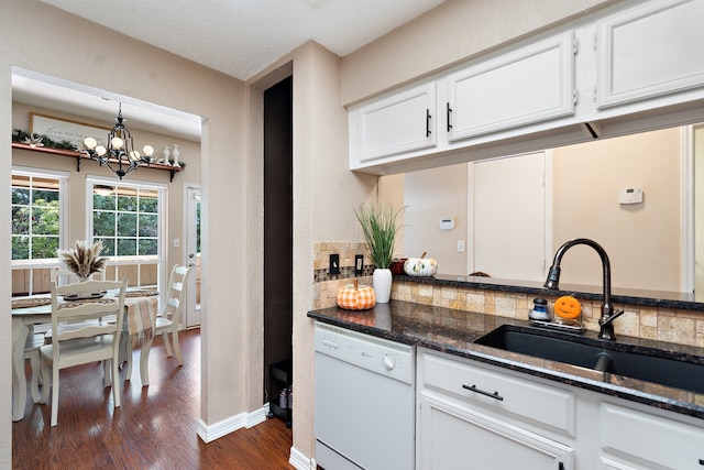 kitchen featuring dishwasher, hanging light fixtures, dark stone countertops, sink, and white cabinetry