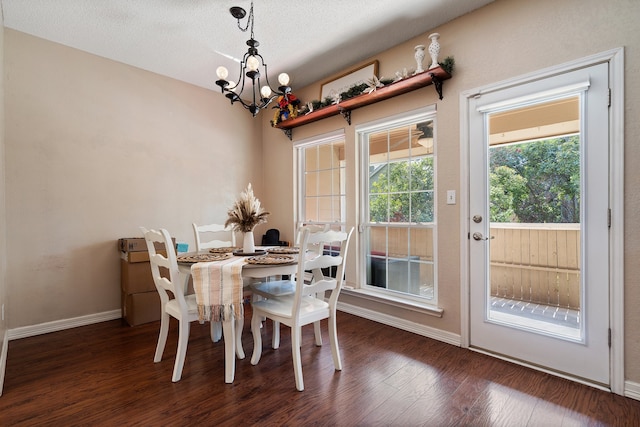 dining area with a textured ceiling, an inviting chandelier, and dark hardwood / wood-style floors