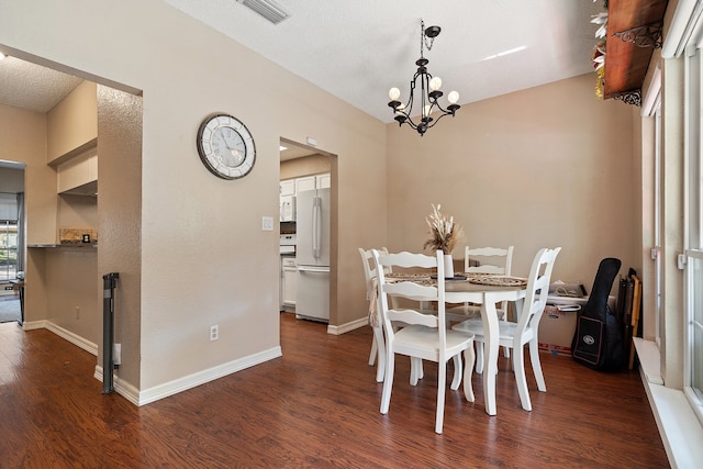 dining area with a textured ceiling, a chandelier, and dark hardwood / wood-style flooring