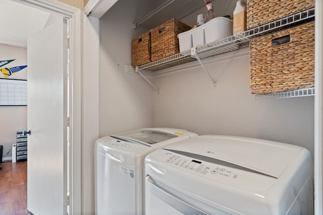 washroom with dark wood-type flooring, washing machine and dryer, and a textured ceiling