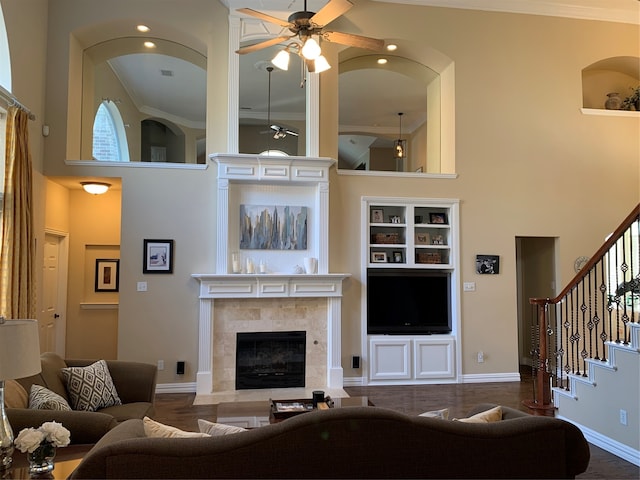 living room featuring a towering ceiling, ornamental molding, a fireplace, and ceiling fan