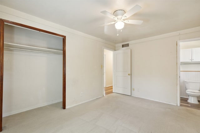 unfurnished bedroom with ensuite bath, light carpet, a closet, and ceiling fan