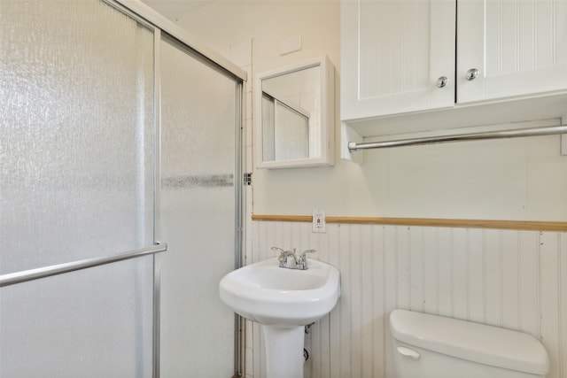 bathroom with wooden walls, a shower with shower door, and toilet