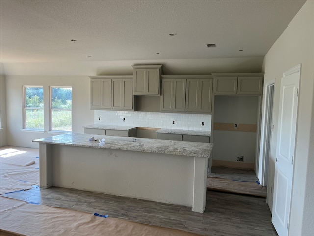 kitchen featuring gray cabinetry, decorative backsplash, a center island, and hardwood / wood-style floors