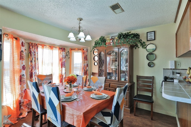 dining space featuring a notable chandelier, dark hardwood / wood-style flooring, and a textured ceiling