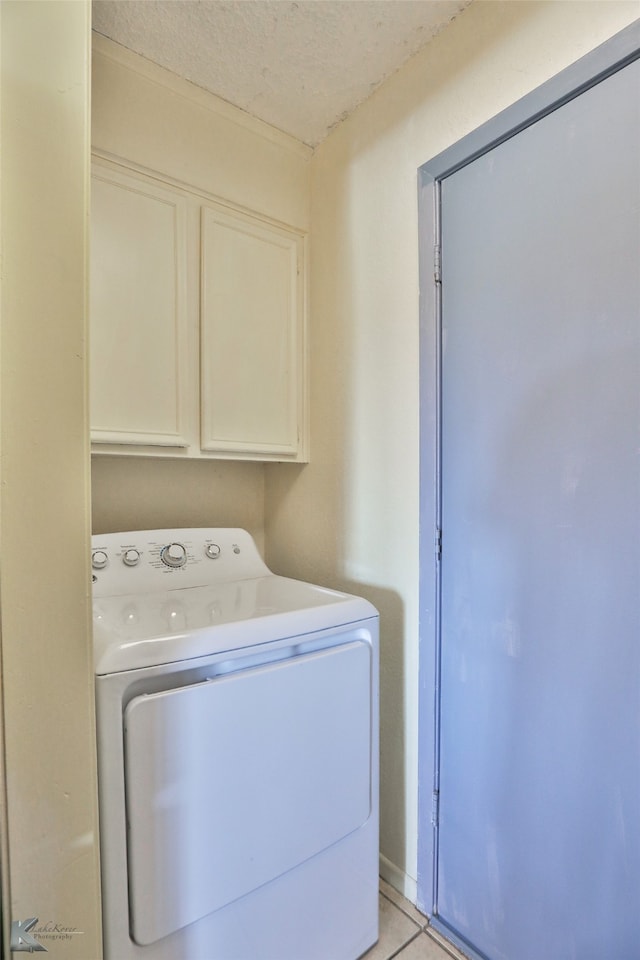 washroom featuring washer / clothes dryer, light tile patterned floors, cabinets, and a textured ceiling