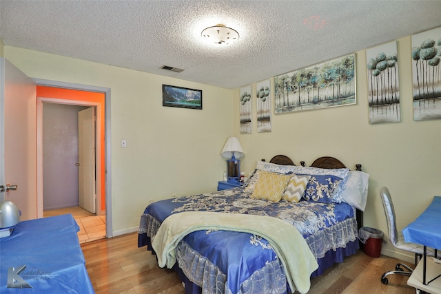 bedroom with hardwood / wood-style floors and a textured ceiling