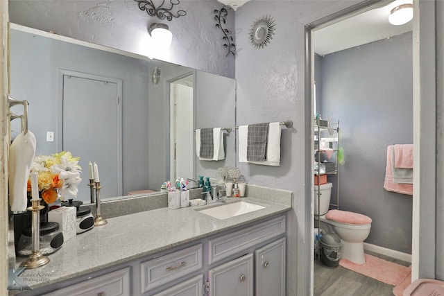 bathroom with hardwood / wood-style flooring, vanity, and toilet