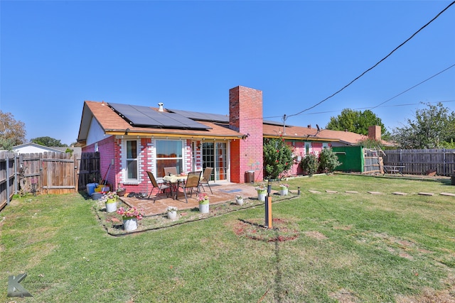 back of house with a patio area, a yard, and solar panels