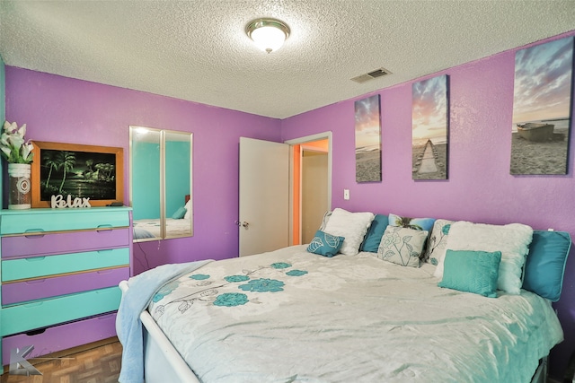 bedroom featuring dark parquet flooring and a textured ceiling