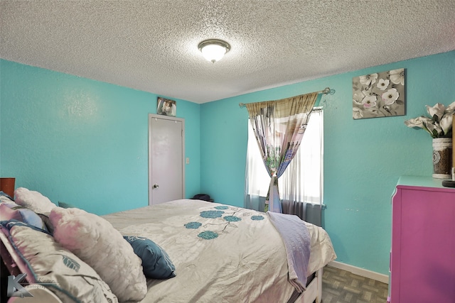 bedroom featuring parquet flooring and a textured ceiling