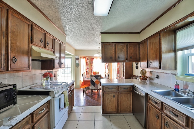 kitchen featuring kitchen peninsula, backsplash, stainless steel appliances, sink, and light tile patterned floors