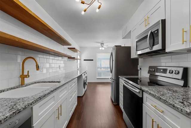 kitchen with white cabinets, light stone countertops, stainless steel appliances, and a sink