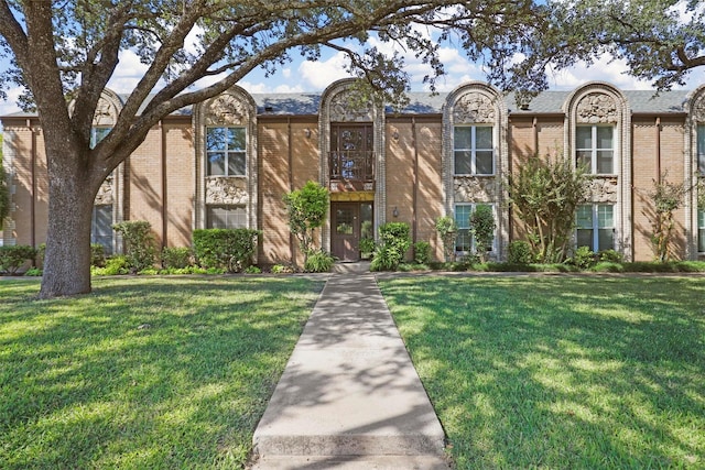 townhome / multi-family property featuring a front lawn and brick siding