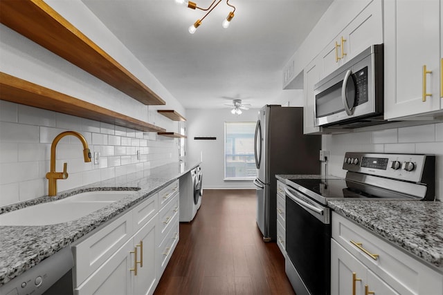kitchen featuring stainless steel appliances, open shelves, a sink, and backsplash