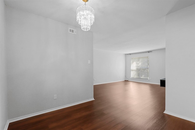 unfurnished dining area featuring a sink, a notable chandelier, baseboards, and dark wood-style flooring