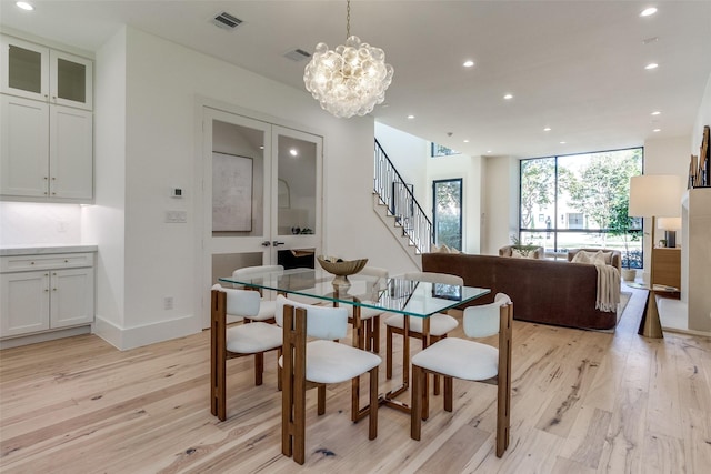 dining room featuring french doors, expansive windows, a notable chandelier, and light hardwood / wood-style floors