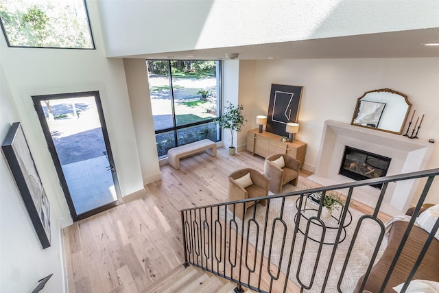 living area featuring a wealth of natural light, light wood-type flooring, a glass covered fireplace, and stairs