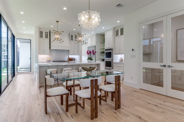 kitchen featuring a center island with sink, sink, light stone countertops, light wood-type flooring, and white cabinetry