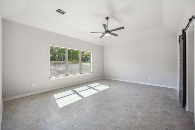 empty room featuring lofted ceiling, a barn door, and ceiling fan