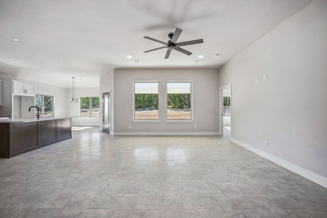 unfurnished living room with a textured ceiling, sink, and ceiling fan