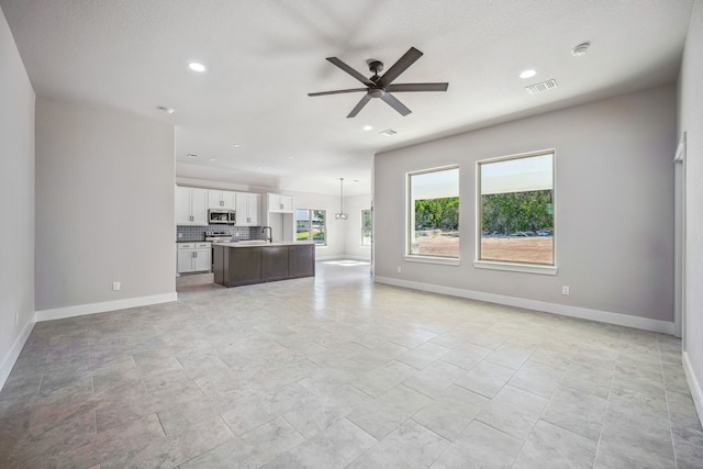 unfurnished living room with a textured ceiling and ceiling fan