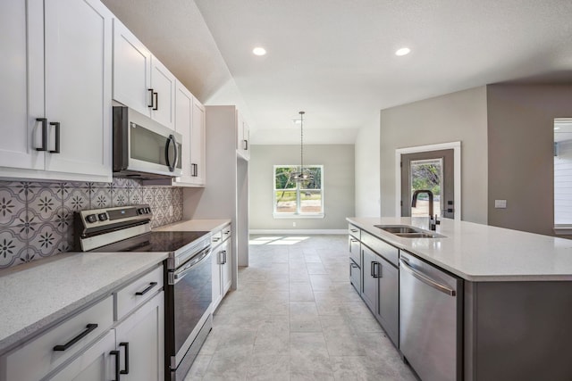 kitchen featuring tasteful backsplash, appliances with stainless steel finishes, sink, pendant lighting, and white cabinets