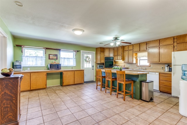 kitchen featuring a kitchen breakfast bar, a center island, white appliances, and light tile patterned floors