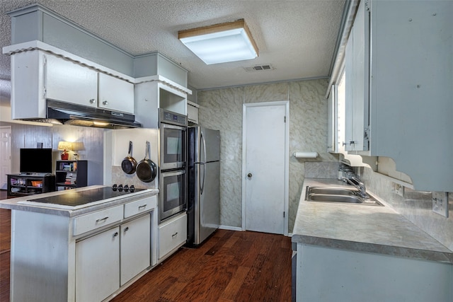 kitchen featuring appliances with stainless steel finishes, sink, a textured ceiling, dark hardwood / wood-style flooring, and white cabinetry