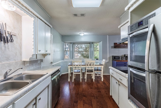 kitchen featuring dark hardwood / wood-style flooring, a textured ceiling, white cabinetry, stainless steel appliances, and sink