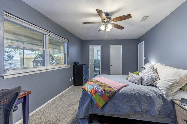 carpeted bedroom with ensuite bath and ceiling fan