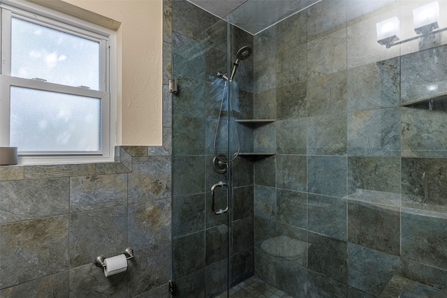 bathroom featuring a healthy amount of sunlight, tile walls, and a shower with shower door